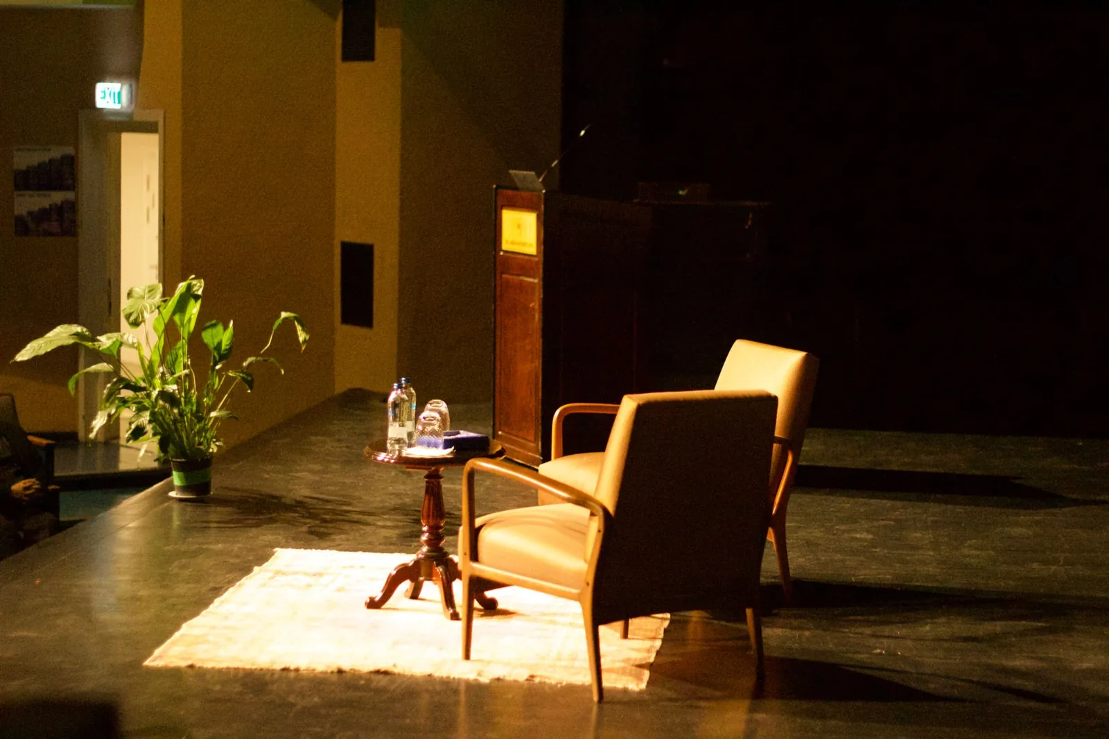 The stage before a session: two armchairs and a small table on a rug, beside the lectern