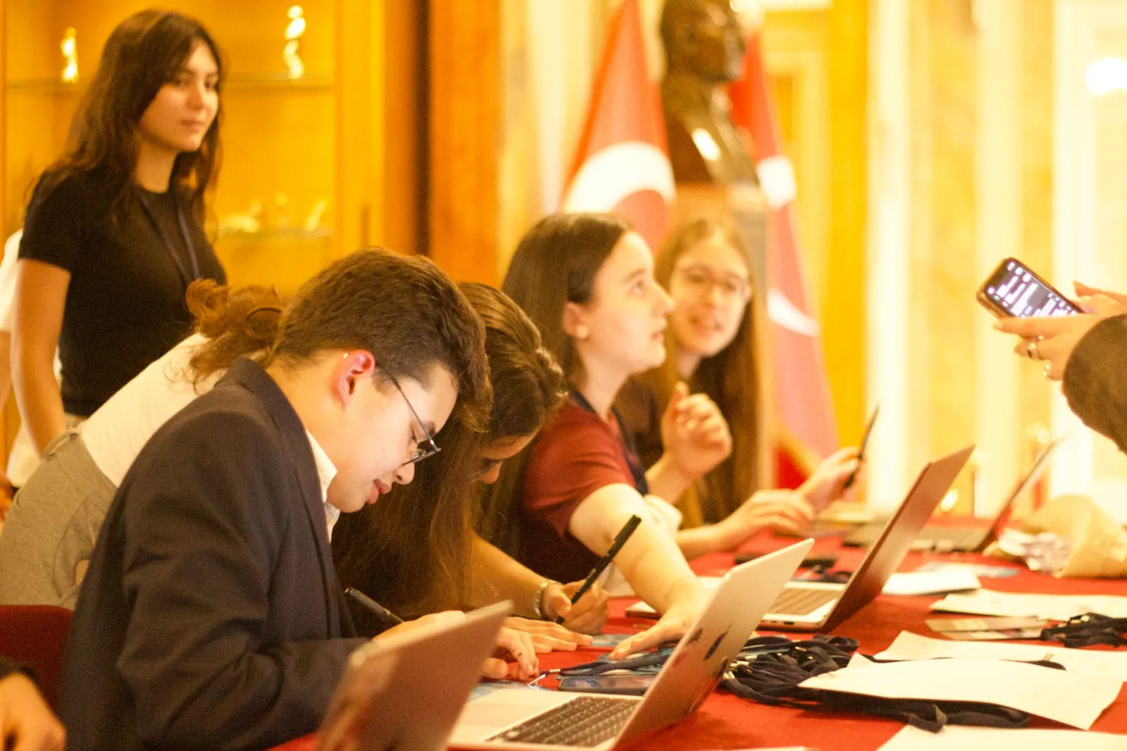 Students at the registration desk working on laptops, with a Turkish flag behind them